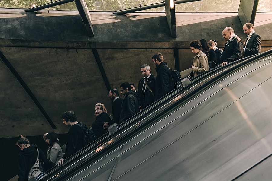 people in suits going down public transit escalator